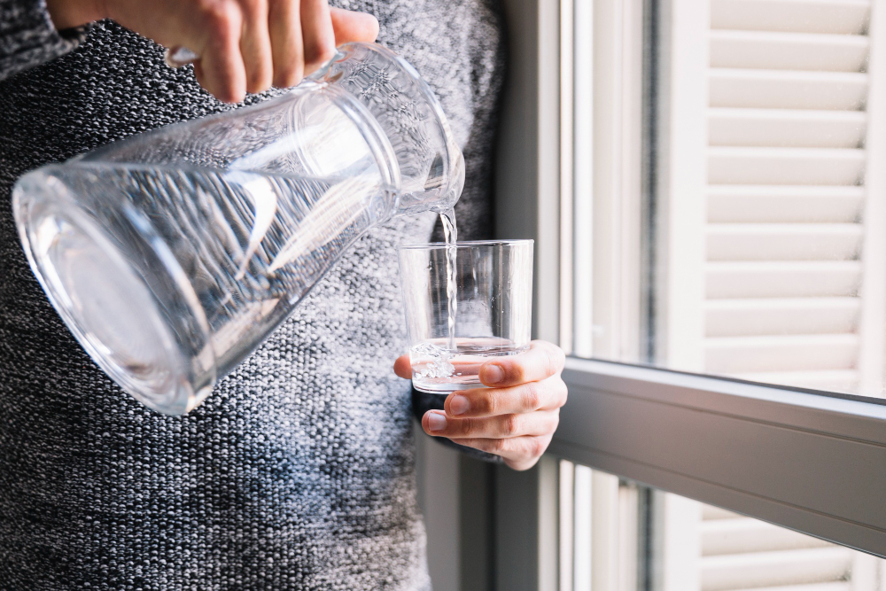 crop-man-pouring-water-near-window